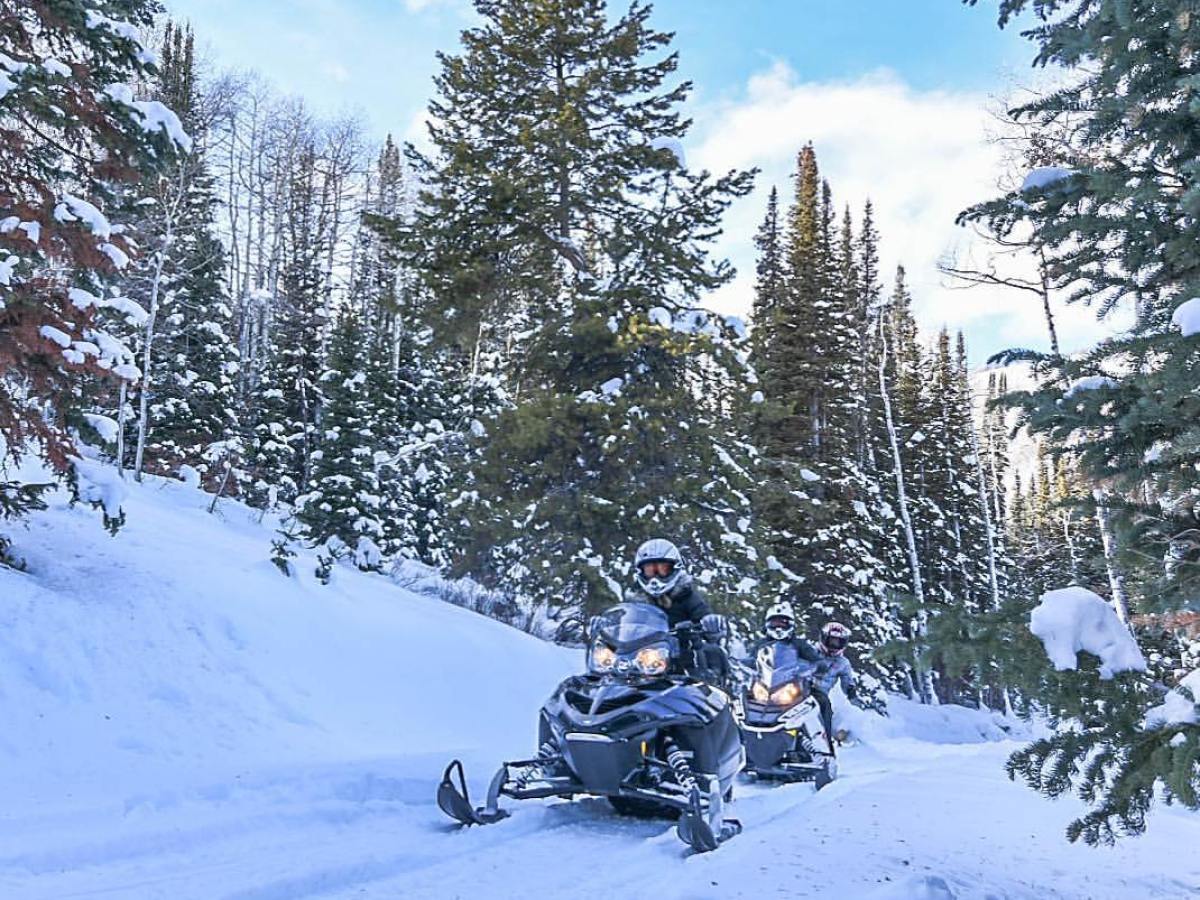 a man riding a motorcycle on the side of a snow covered slope